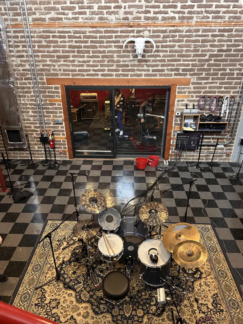 Studio session overhead view with drum kit and control room window